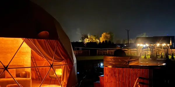 Oświetlona kopuła glampingowa z jacuzzi nocą w Bieszczadach